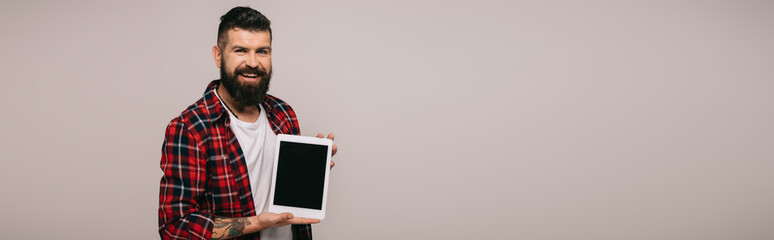 Wall Mural - cheerful man showing digital tablet with blank screen, isolated on grey