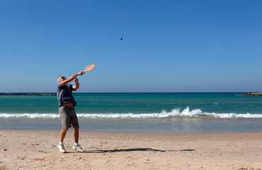 Wall Mural - handsome mature man playing tennis on the beach