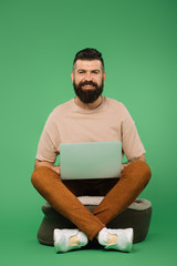 Wall Mural - smiling bearded man using laptop isolated on green