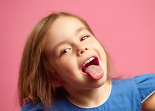 Close Up Shot Of Little Girl With Her Tongue Out Over Pink Isolated.
