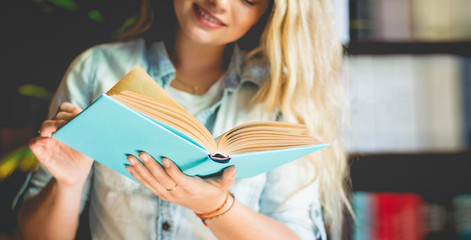 International exchange Students Curly hair, golden color Are standing at the bookshelf in the library and reading the book in hand In the education and recreation concept, Vintage Style and soft tone.