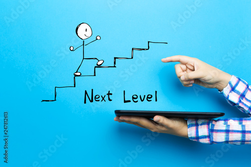 Fotomural Next level concept with a tablet computer on a blue background
