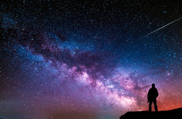 beautiful starry night, man silhouette with a camera looking at the milky way galaxy.