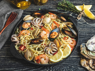 Cooked pasta with clams, shrimps, baby octopus, mussels tomato on a frying pan , spaghetti. Close up