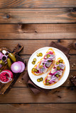 Fototapeta Zwierzęta - Delicious grilled sandwiches with herring, onion and beetroot sauce with horseradish on dark wooden rustic background. Danish cuisine. Top view