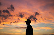 © Cavan Images - Side view of man standing against cloudy sky during sunset