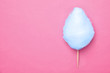Stick with blue yummy cotton candy on pink background, top view. Space for text