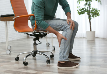 Wall Mural - Man suffering from leg pain indoors, closeup