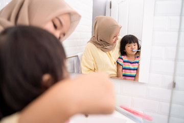 Wall Mural - asian muslim mom brush her kid's teeth in the bathroom