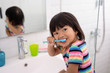 © Odua Images - asian little girl brushes her teeth alone in the bathroom and her head looks when called by her mother