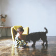 © Yumiko Kinoshita - Side view of girl with dog sitting on floor at home