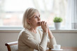 © fizkes - Thoughtful woman sitting at table with cup of tea