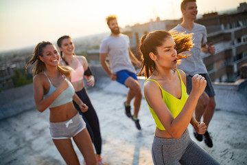 Group of young happy people friends exercising outdoors at sunset.