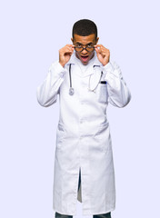 Wall Mural - Young afro american man doctor with glasses and surprised on isolated background