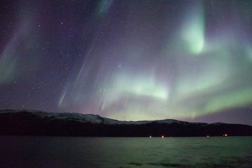 northern lights in norway in green, blue and violet colours and mountains in the distance