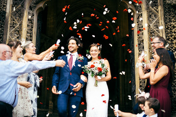 Family throwing rose petals at the newly wed bride and groom