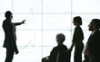 © JonoErasmus - Silhouettes of black african businessman giving a presentation at a business conference to group. Large video screen with charts and graphs in front of him and team