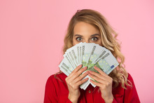 Beautiful Young Girl In A Red Shirt With Euros In Hands On A Pink Background With A Surprised Face