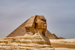 The head of the Great Sphinx against the backdrop of the pyramid of Cheops (Khufu), the Great Pyramid of Giza - the largest of the Egyptian pyramids - on a sunny day. Cairo, Egypt, Africa.