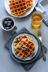 Wall Mural - Belgian waffles with blueberries and honey on gray wooden background. Homemade healthy breakfast. Selective focus