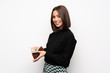 © luismolinero - Young woman over white wall holding a wallet