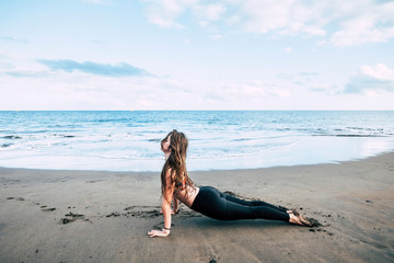 Wall Mural - Plank fitness hard position at the beach with beautiful brunette girl enjoying a helthy sport fitness lifestyle outdoor - blue ocean horizon in background for summer exercises concept