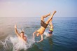 Young people jumping inside ocean in summer excursion day. Happy crazy friends diving from sailing boat into the sea. Vacation, youth, travel and fun concept
