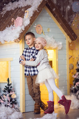 brother and sister 6-7-8 years old, happy children, a girl in a hat on Christmas eve, light colors near the house