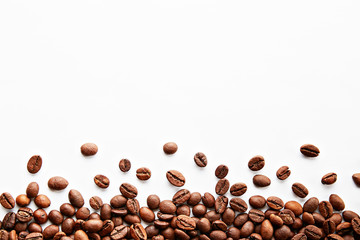 Roasted brown coffee beans scattered on white table with a lot copy space for text. Flat lay composition. Close up, top view, background.