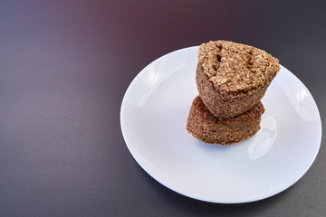 high quality dietary homemade bread two rolls on top of each other on a white plate and a dark background. healthy food on the table. fresh bread. copy space