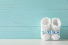 Handmade Baby Booties On Table Against Wooden Background. Space For Text