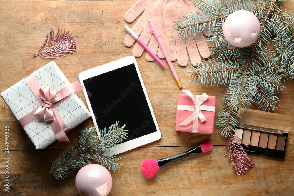 Christmas composition with tablet PC, gift box and female items on wooden background