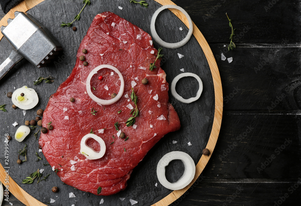 Board with tasty raw meat and spices on wooden table