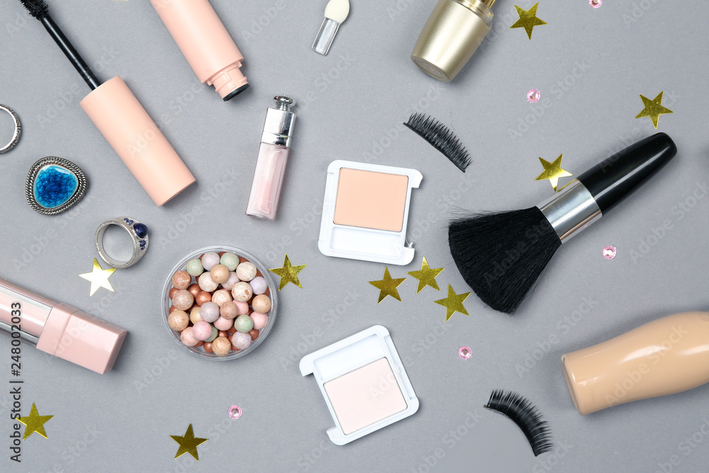 Set of makeup cosmetics with accessories on grey background