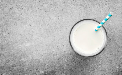 Glass of fresh milk with drinking straw on a concrete background. Pure milk, soy milk or cow milk and copy space.