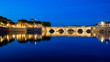 Tiberius bridge at night. Rimini, Italy. City lights reflected in the water.