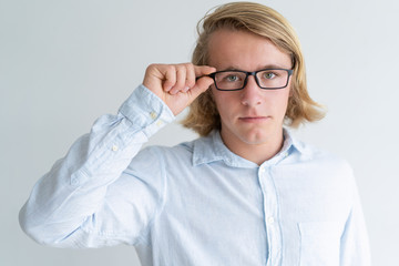 Wall Mural - Serious young fair-haired man adjusting glasses