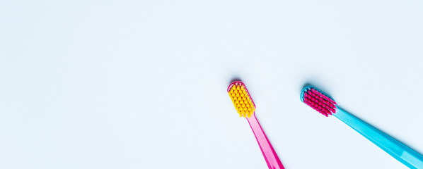 Wall Mural - Colorful tooth brushes with bright color bristles on a light pastel blue background. Long wide banner of teeth care frame concept mockup with empty space for text.