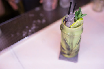 Green exotic tasty healthy Cocktail drink with burning cinnamon and lime, mint beverage on a bar counter. Selective focus. Top view. Trendy stylish edit. Copy paste space design service barman