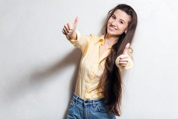 Cheerful young girl showing thumbs up over white studio background.