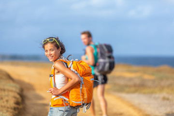 Young happy couple hiking together in nature outdoor. Travel adventure young tourists walking with backpacks in mountain by the ocean.