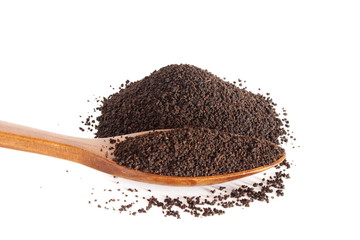 Dry black tea heap with wooden spoon on white background