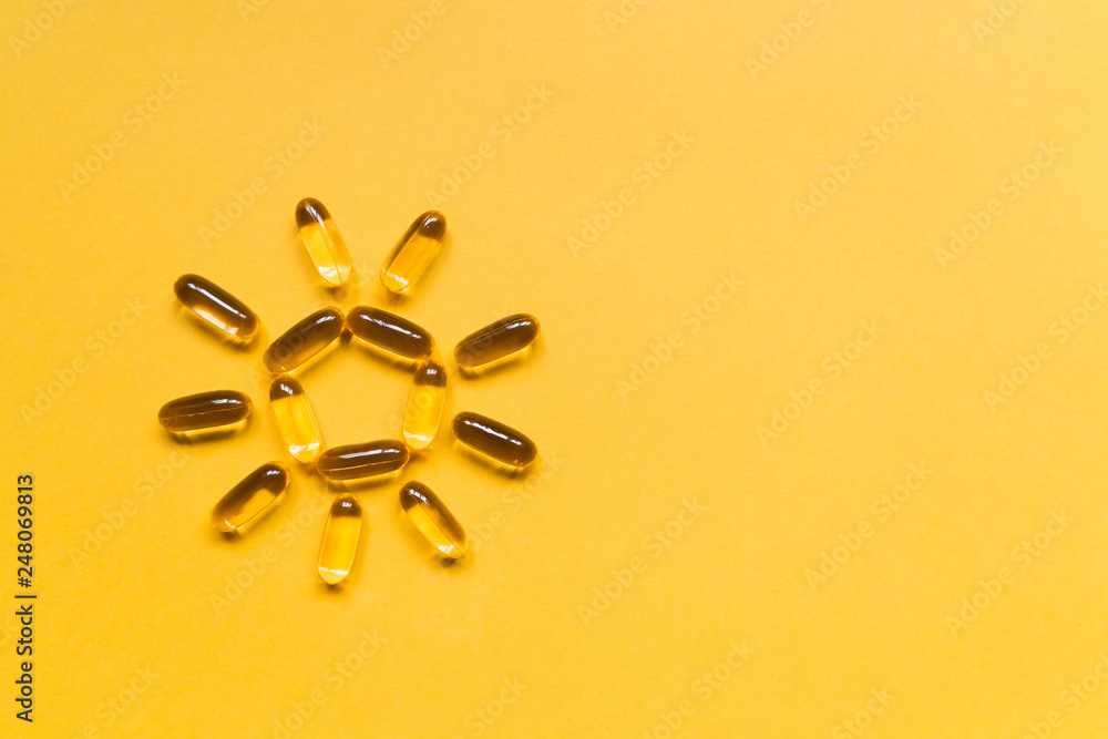 Obraz na płótnie Close up capsules of fish fat oil in the sun shape, omega 3, vitamin e on the yellow background. Healthy food diet. Nutritional supplement w salonie