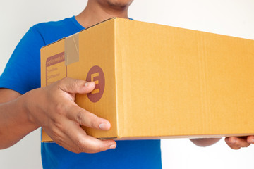 Closeup hands of delivery man holding package to deliver. Courier hand holding brown box isolated on white background.