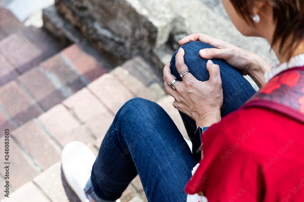 Woman seated in pain with knees on stairs
