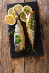 Wall Mural - Whole freshly smoked mackerel served with lemons and parsley closeup on a slate board on the table. Vertical top view