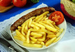 Plato con una salchicha frankfurt y patatas fritas.
