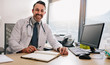 © Jacob Lund - Confident doctor sitting at his clinic desk