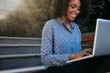 © Jacob Lund - Businesswoman sitting on steps outdoors working on laptop