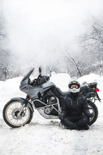 Rider Man And Adventure Motorcycle. Snowy Day. Meditating In The Lotus Position That Used To End The Winter. Travel Tour, Active Life Style Concept. Winter Clothes, Equipment, Vertical Photo